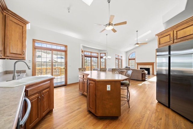 kitchen featuring a sink, a kitchen bar, high quality fridge, and brown cabinetry