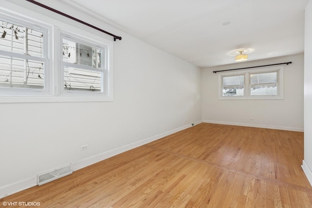 unfurnished room with light wood-style flooring, baseboards, and visible vents