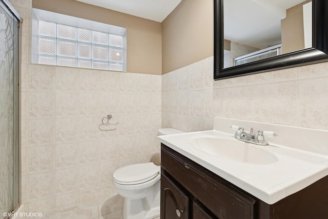 bathroom featuring vanity, a shower with shower door, tile walls, toilet, and tile patterned floors