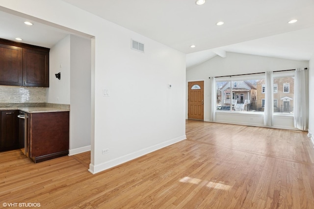 unfurnished living room featuring visible vents, baseboards, lofted ceiling with beams, and light wood-style floors