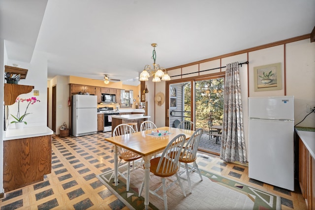 dining space with light floors and ceiling fan with notable chandelier