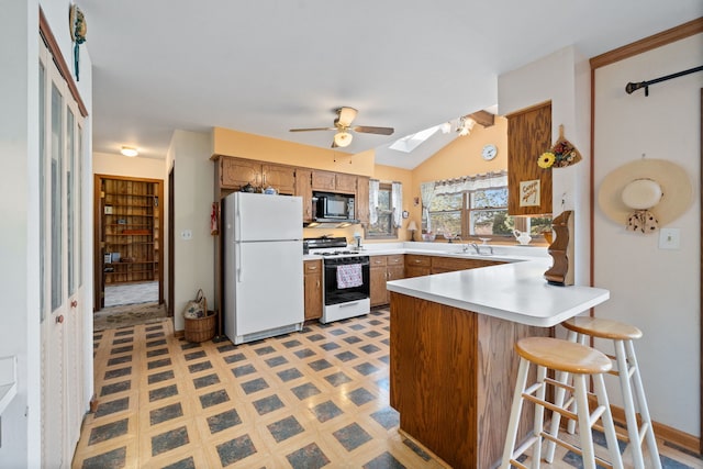 kitchen featuring white appliances, a peninsula, light countertops, light floors, and ceiling fan