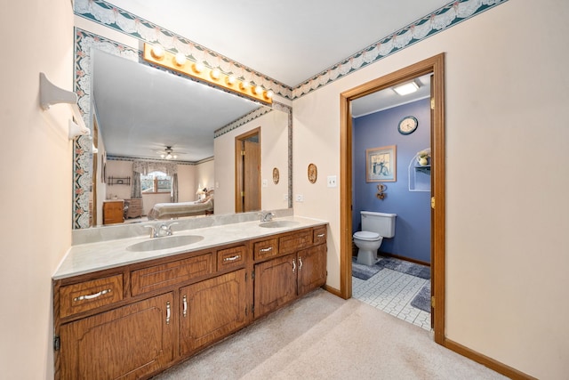 bathroom with a sink, baseboards, toilet, and double vanity