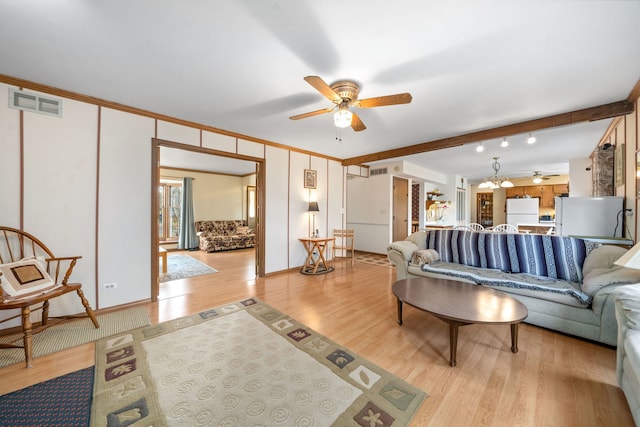 living room with ornamental molding, light wood-style floors, visible vents, and ceiling fan