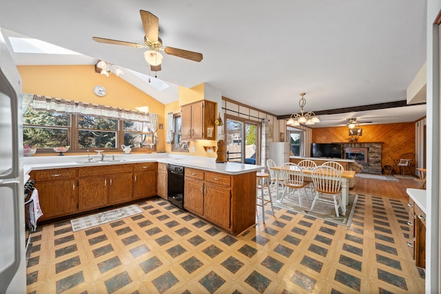 kitchen featuring a ceiling fan, open floor plan, wooden walls, a peninsula, and light countertops