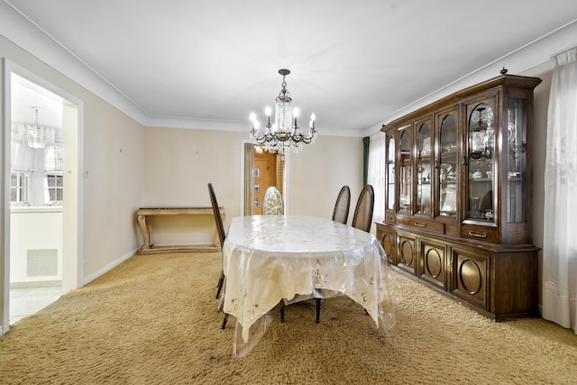 dining room with visible vents, ornamental molding, baseboards, light colored carpet, and a chandelier