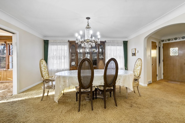 dining space featuring a chandelier, arched walkways, a wealth of natural light, and light carpet