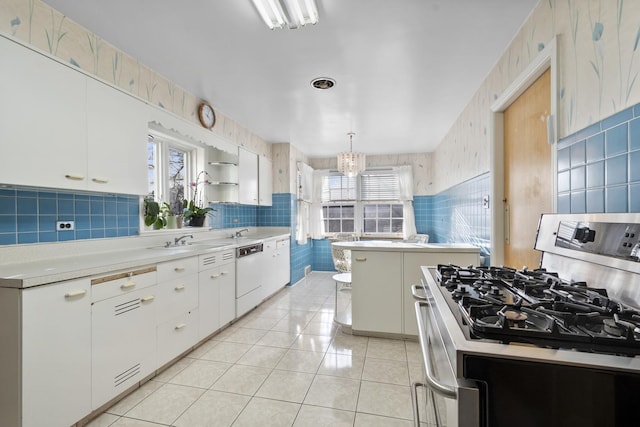 kitchen featuring light tile patterned floors, gas range, plenty of natural light, and white dishwasher