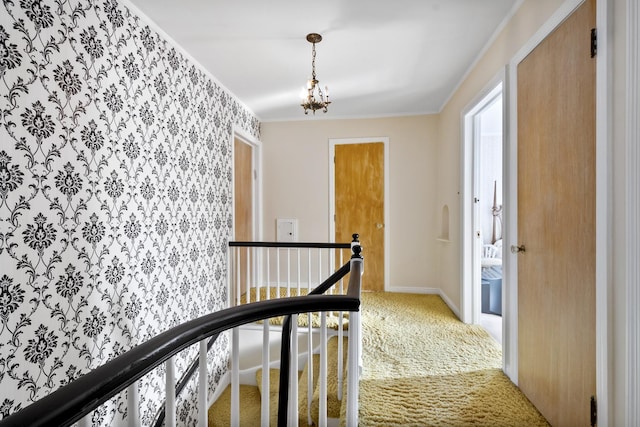 hallway featuring an upstairs landing, light colored carpet, crown molding, and baseboards