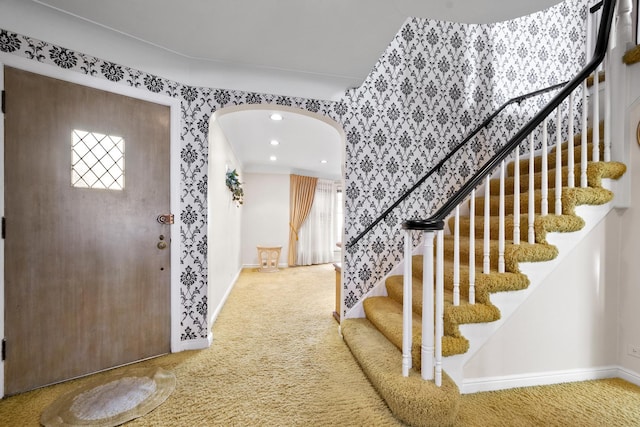 foyer with arched walkways, carpet flooring, recessed lighting, and baseboards