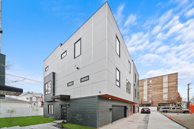 view of building exterior featuring an attached garage and fence