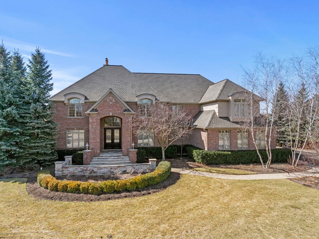22182 N Prairie Ln, Kildeer, IL 60047 - french country inspired facade with brick siding, french doors, roof with shingles, and a front yard