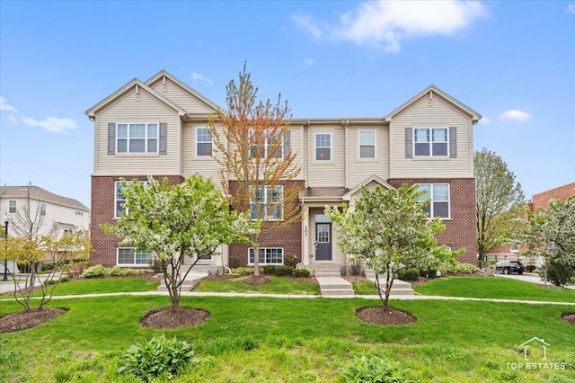 townhome / multi-family property with brick siding and a front lawn