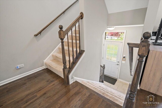 staircase featuring wood finished floors, baseboards, and lofted ceiling