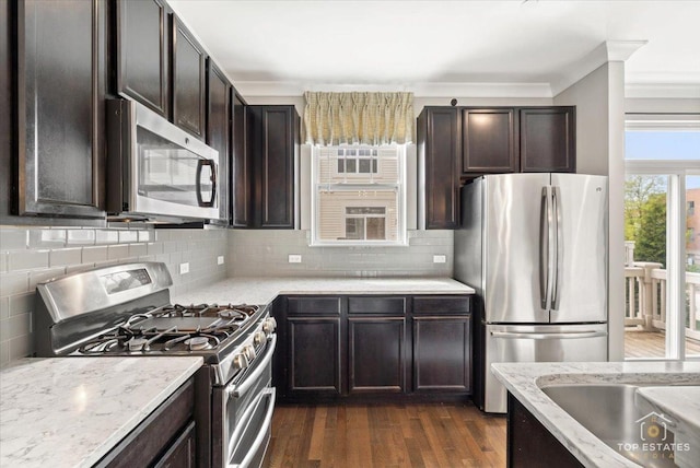 kitchen with stainless steel appliances, dark brown cabinets, dark wood-style floors, tasteful backsplash, and crown molding