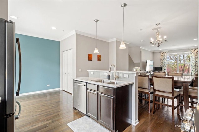 kitchen featuring stainless steel appliances, a sink, dark wood finished floors, open floor plan, and light countertops