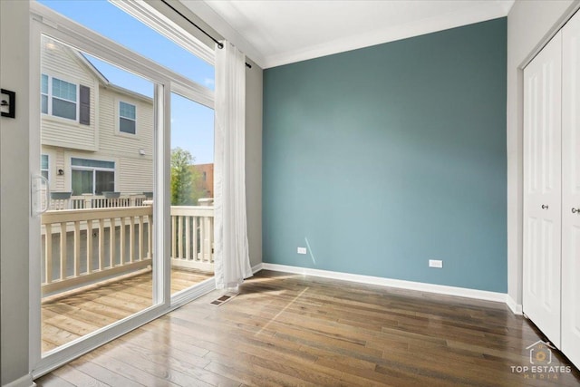 interior space featuring hardwood / wood-style floors, baseboards, and crown molding
