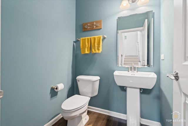 bathroom with wood finished floors, toilet, and baseboards