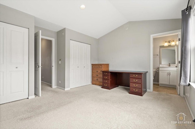unfurnished bedroom featuring carpet, vaulted ceiling, baseboards, and ensuite bath