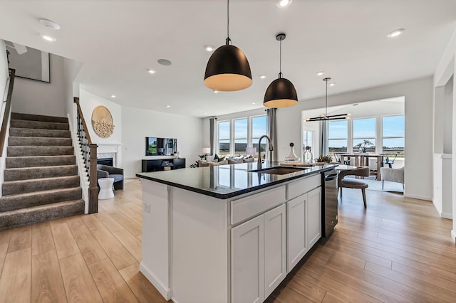 kitchen with a sink, a healthy amount of sunlight, open floor plan, and light wood finished floors