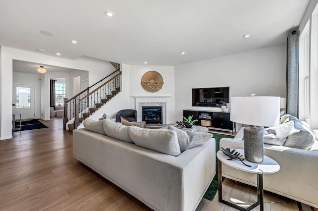 living area with stairway, recessed lighting, wood finished floors, and a premium fireplace