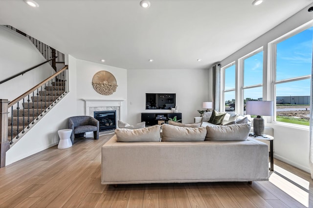 living area featuring recessed lighting, stairway, light wood-style floors, a premium fireplace, and baseboards