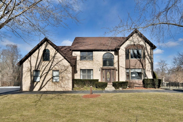 tudor house with a front yard and brick siding