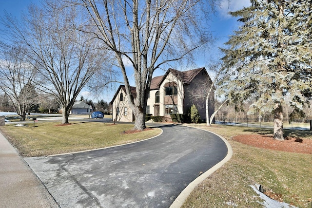 view of front of house featuring aphalt driveway, a front yard, and fence