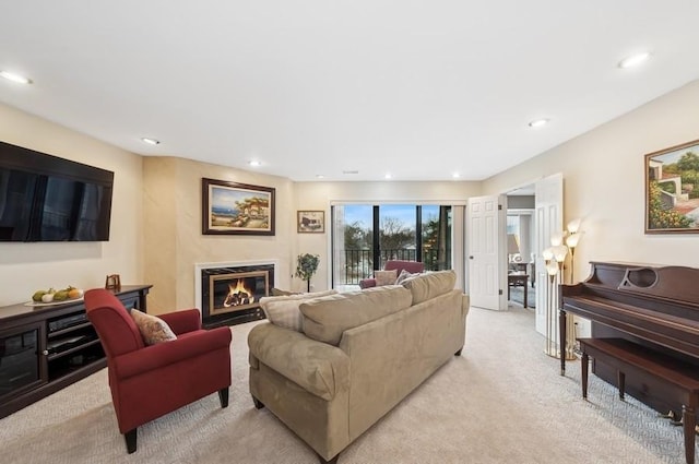 living area featuring a glass covered fireplace, recessed lighting, and light carpet