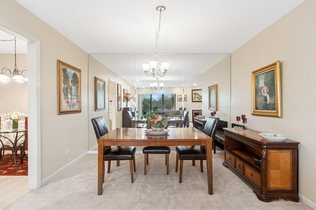 dining space with an inviting chandelier, light colored carpet, and baseboards