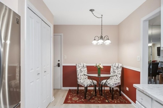 dining space featuring baseboards, light wood-type flooring, and an inviting chandelier