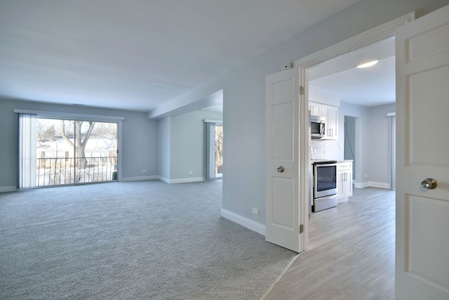 empty room featuring light colored carpet and baseboards