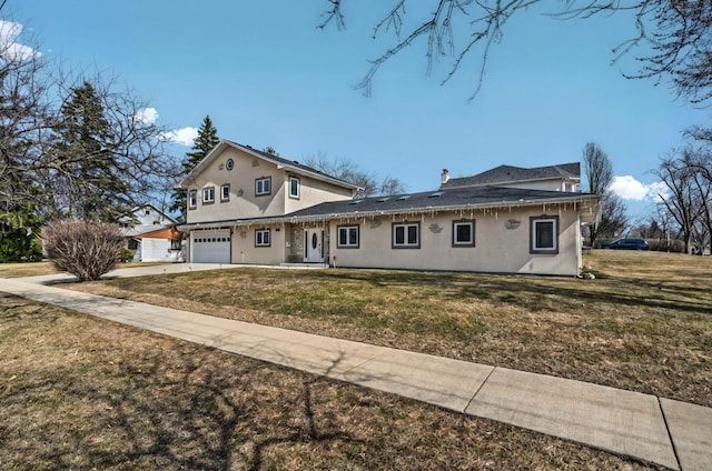 traditional-style house with concrete driveway, a front yard, and stucco siding