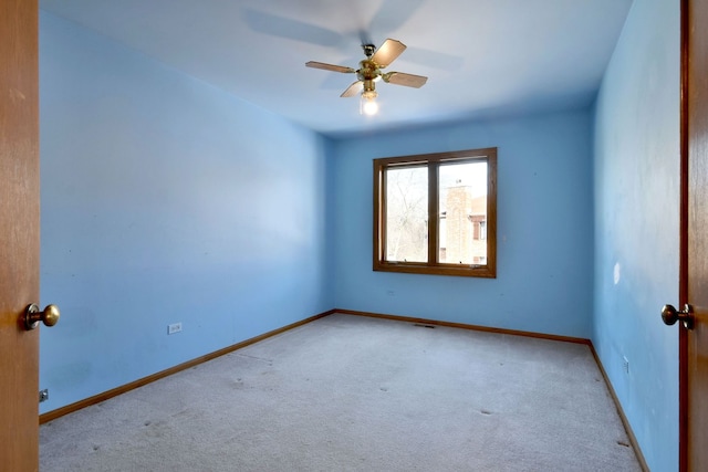 carpeted empty room with visible vents, baseboards, and a ceiling fan