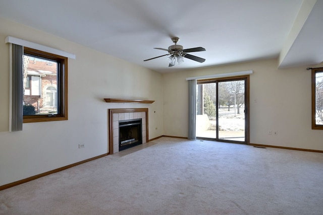 unfurnished living room with carpet flooring, ceiling fan, a fireplace, and baseboards