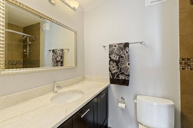 bathroom featuring tiled shower, toilet, and vanity