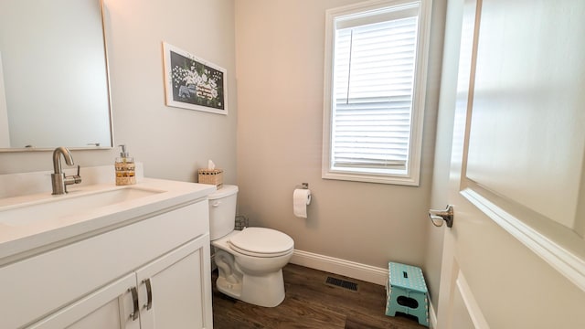 1617 Oliger Dr, Mahomet, IL 61853 - half bathroom with vanity, wood finished floors, visible vents, baseboards, and toilet