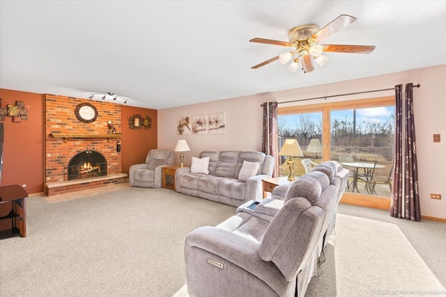 carpeted living room with baseboards, a ceiling fan, a brick fireplace, and rail lighting