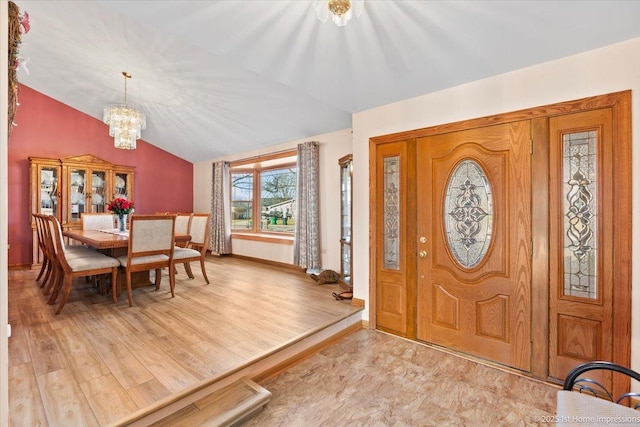 foyer entrance featuring lofted ceiling, baseboards, light wood finished floors, and a chandelier