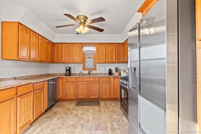 kitchen with a sink, light stone countertops, appliances with stainless steel finishes, and brown cabinets