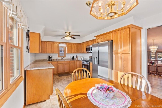 kitchen featuring ceiling fan with notable chandelier, stainless steel appliances, light countertops, and a sink