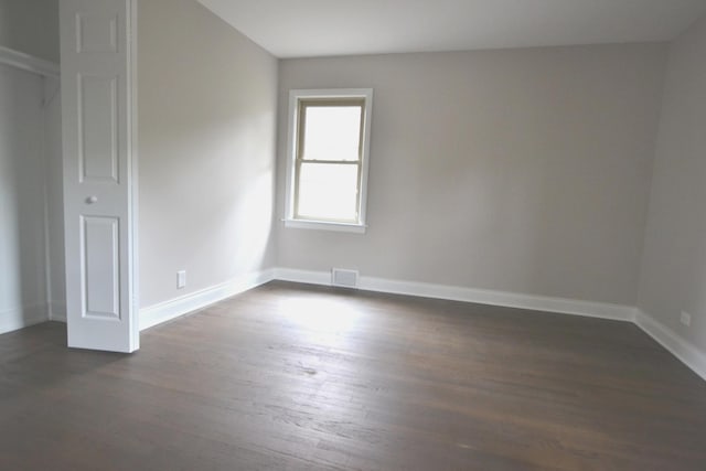 spare room with visible vents, baseboards, and dark wood-style flooring