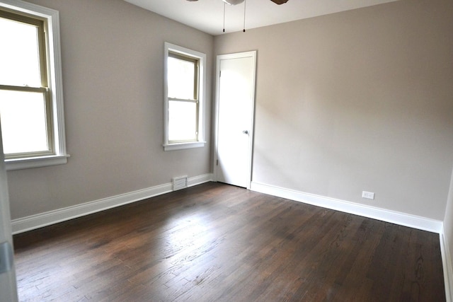 empty room featuring visible vents, dark wood-style floors, baseboards, and ceiling fan