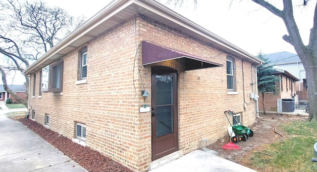 view of side of home featuring cooling unit and brick siding