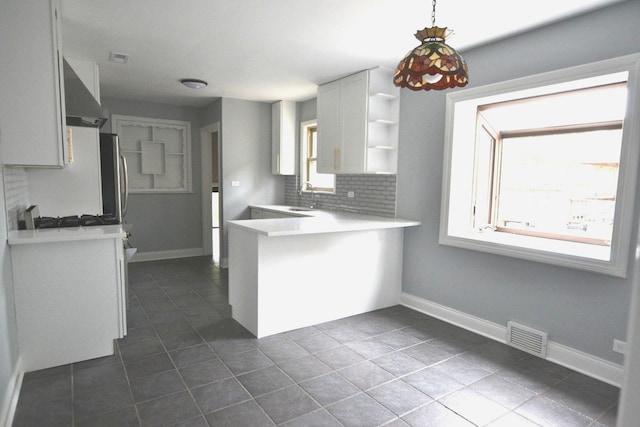 kitchen featuring visible vents, open shelves, a peninsula, wall chimney exhaust hood, and backsplash