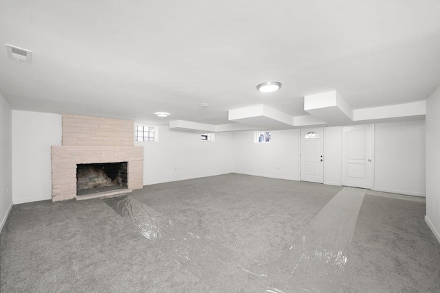 below grade area featuring visible vents, carpet flooring, a fireplace, and baseboards