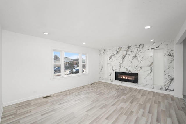 unfurnished living room featuring visible vents, recessed lighting, a fireplace, and light wood-style floors