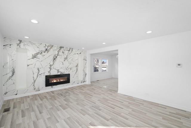 unfurnished living room with light wood finished floors, visible vents, recessed lighting, and a fireplace