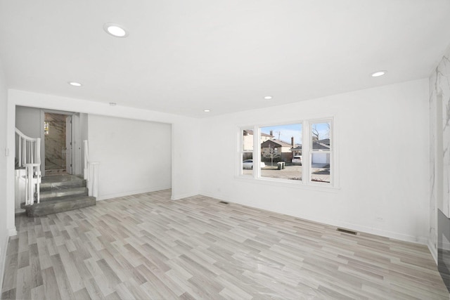 unfurnished room with visible vents, baseboards, stairs, recessed lighting, and light wood-style floors