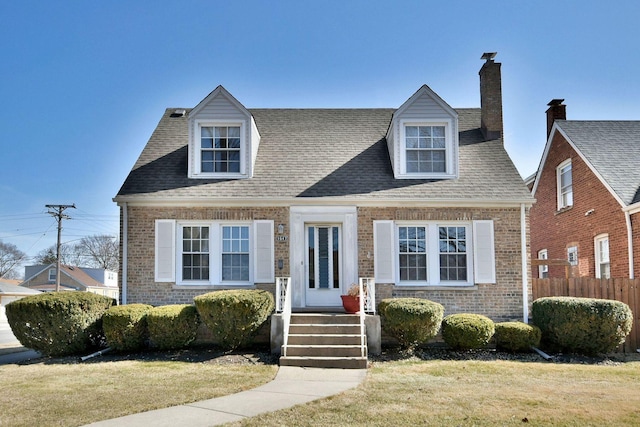 cape cod home featuring brick siding, a front lawn, and fence